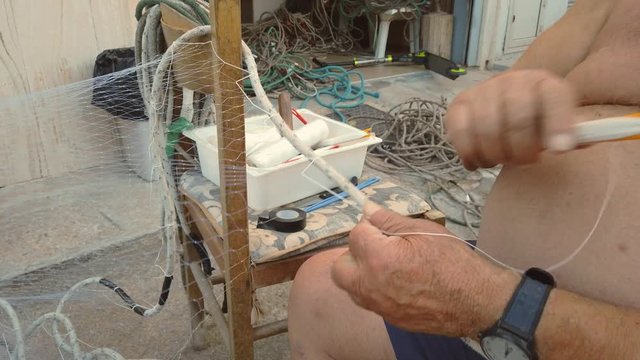 esperto e anziano pescatore prepara le reti da pesca