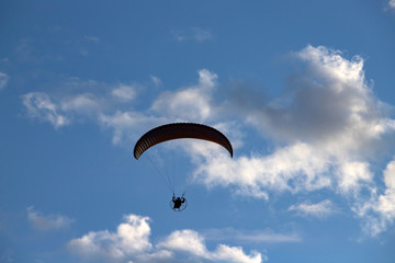 Paraglider silhouette over blue sky.