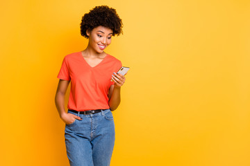 Copyspace photo of beautiful cheerful cute charming gorgeous girlfriend standing confidently wearing t-shirt jeans denim holding phone isolated over yellow color vivid background