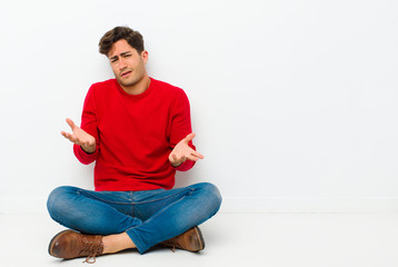 young handsome man looking puzzled, confused and stressed, wondering between different options,...