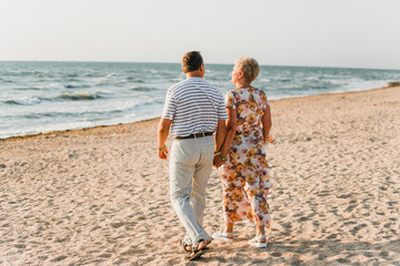 Romantic adult couple standing together on the beach. Mature pair relax at the seaside on holiday....