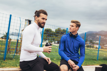 Young athletes practicing a run on athletics stadium track, having break.