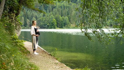 Beautiful pregnant woman near a mountain lake in the forest.