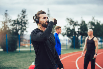 Young athletes practicing a run on athletics stadium track, having break.