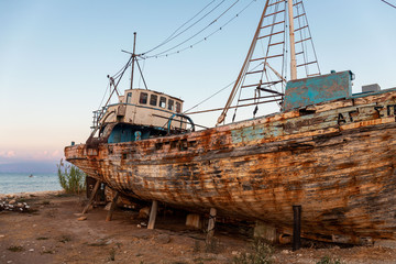 Old wooden fishing boat on the shore while sunset