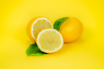Whole and halved lemons on yellow background