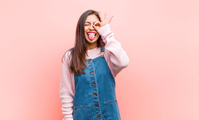 young  pretty woman smiling happily with funny face, joking and looking through peephole, spying on...
