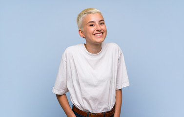 Teenager girl with white short hair over blue wall laughing