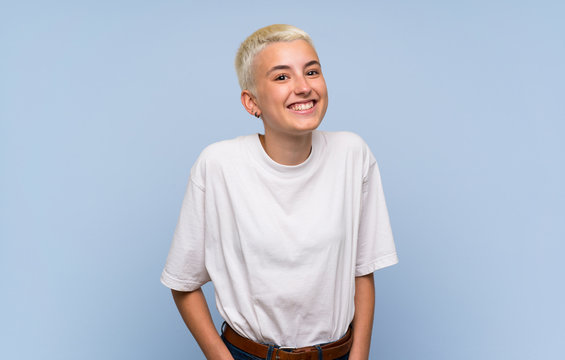 Teenager girl with white short hair over blue wall laughing
