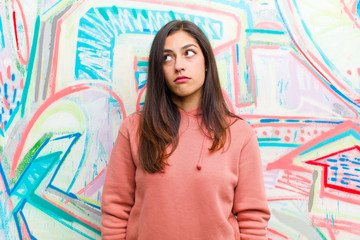 with a worried, confused, clueless expression, looking up to copy space, doubting