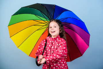 Enjoy rain concept. Fall season. Kid girl happy hold colorful rainbow umbrella. Rainy weather with proper garments. Rainy day fun. Happy walk under umbrella. There is rainbow always after the rain