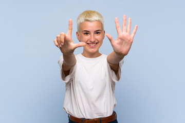 Teenager girl with white short hair over blue wall counting seven with fingers