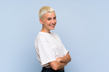 Teenager girl with white short hair over blue wall with arms crossed and looking forward