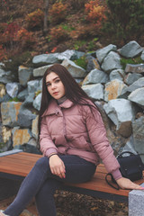 Portrait of a young tired pretty pregnant girl in a pink warm down jacket. Late autumn, the cold is coming. toned photo.