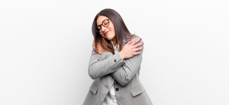 young pretty woman feeling in love, smiling, cuddling and hugging self, staying single, being selfish and egocentric isolated against white wall