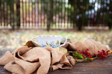 Autumn still life with cup of tea, plaid and leaves on wooden background