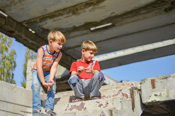 Two children are sitting on the steps of an abandoned building, a concept of the life of street...