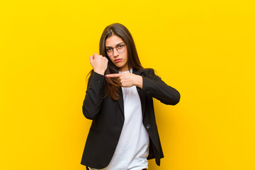 young  pretty woman looking impatient and angry, pointing at watch, asking for punctuality, wants...