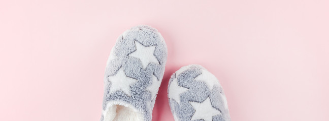 Soft fluffy slippers on pink background