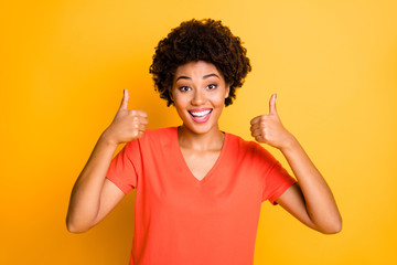 Photo of charming cute cheerful black afro americal lady smiling toothily wearing t-shirt showing you double thumb up while isolated with yellow vibrant color background