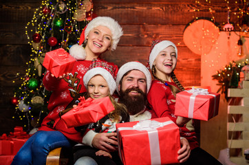Obraz na płótnie Canvas Cheerful family concept. Father Santa claus and mother little daughters christmas tree background. Christmas tradition. Christmas joy. Happy holidays. Parents and children opening christmas gifts