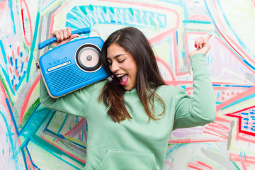 young pretty woman with a vintage radio against graffiti wall