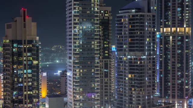 View of various skyscrapers and towers in Dubai Marina from above aerial night timelapse. Illuminated modern buildings in urban skyline