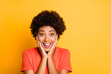 Close up photo of cheerful cute charming attractive girlfriend black smiling toothily holding her cheeks with hands isolated over yellow vivid color background