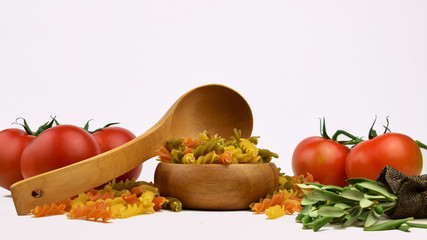 Espirales de colores, tomates rojos de fondo y utensilios de cocina