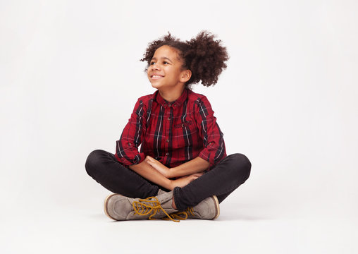Cute teenage girl in casual stylish clothes sitting against white background