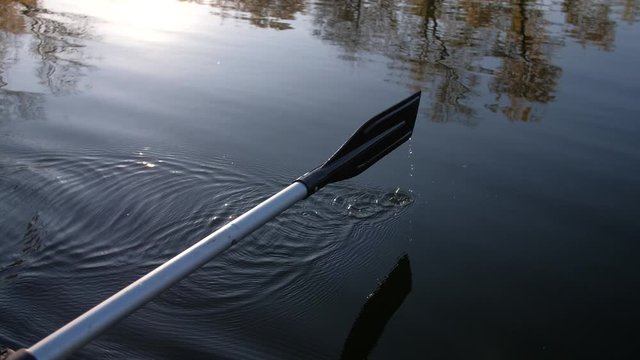 Fisherman rowing inflatable rubber fishing boat on the water surface. Man hand rowing paddle.