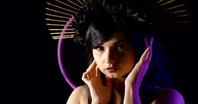 Close-up portrait of a girl in the image of the virgin Mary on a black background with neon lights. Smooth gentle movements of the hands at the face of the model