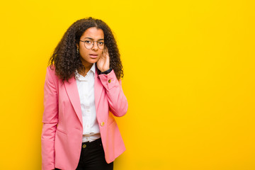 black business woman looking serious and curious, listening, trying to hear a secret conversation...
