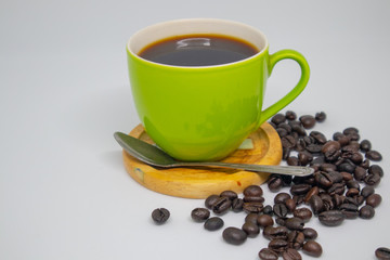 Black coffee in a green mug and coffee beans resting