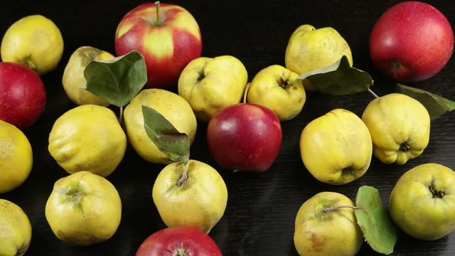 Ripe quince and red apples on a dark wooden table, background