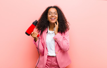 young black pretty woman with a hairdesser against pink wall background