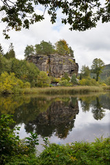 Fototapeta na wymiar Impregnable medieval rock castle Sloup from the 13th century with Castle pond in northern Bohemia, Czech Republic