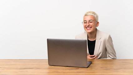Teenager girl with short hair with a laptop smiling a lot