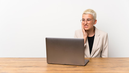 Teenager girl with short hair with a laptop with toothache