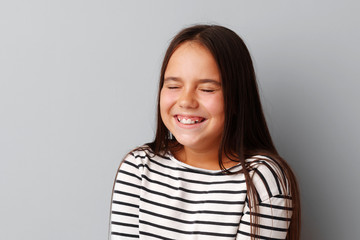 Fototapeta premium Portrait of joyful little girl laughing over a gray background