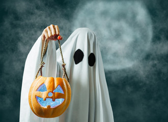 Halloween white ghost holding jack-o-lantern lighting pumpkin.