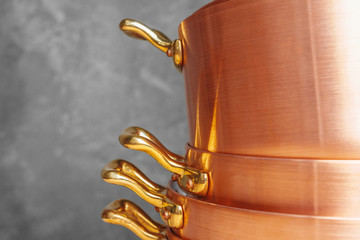 Stack of copper cooking pans on wooden table close up