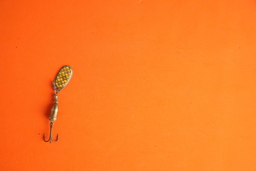 Teaspoon-shaped fishing lure on color background