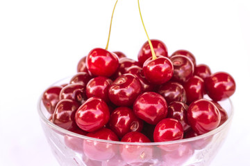 Ripe and juicy cherries in a glass bowl, red sweet cherry, organic fruit, summer food, close-up, isolated on white background