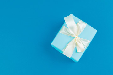 Flat lay of gift box decorated with bow on blue background