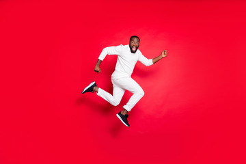 Fototapeta na wymiar Full length profile photo of excited dark skin guy jumping high running x-mas shopping need buy many presents wear white sweater trousers isolated red background