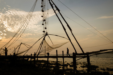 Fishermen working at the chinese fishing nets at evening, Kochi, Kerala, India