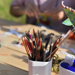Color pencils and glue close-up on a blurred background background of hands making paper crafts