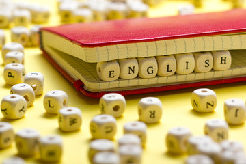 Word english made with block wood letters next to a pile of other letter over wooden table.