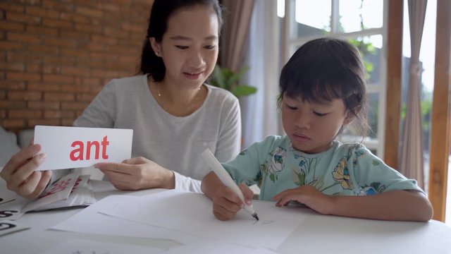 mother and daughter learning to read and write letter at home together. homeschooling activity